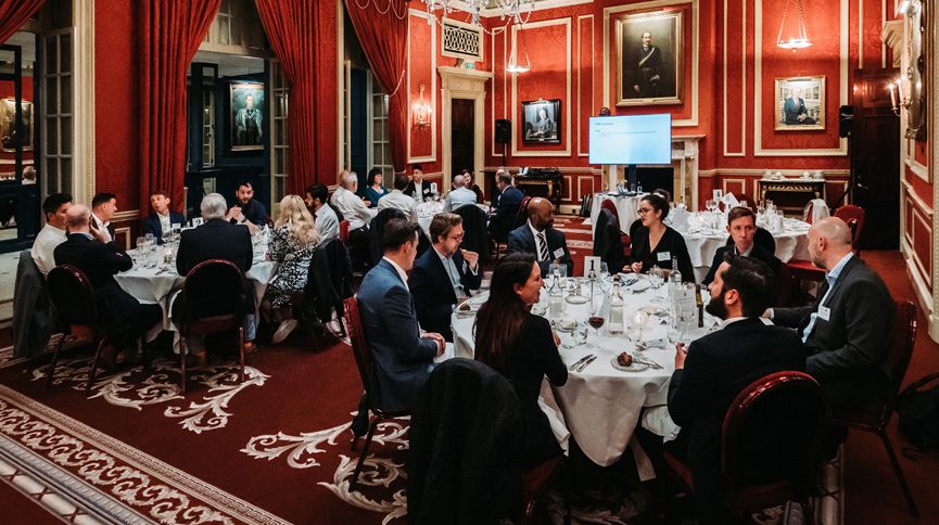 Introhive and partner Consalia seated for dinner in a red ballroom at the Royal Automobile Club.