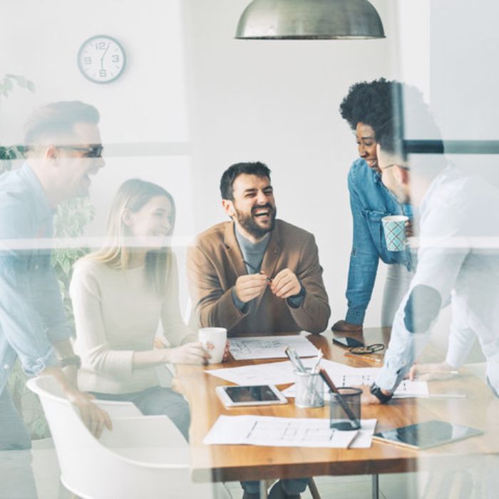 Team meeting around a table, illustrating how contact management software helps firms organize relationship data before CRM implementation.