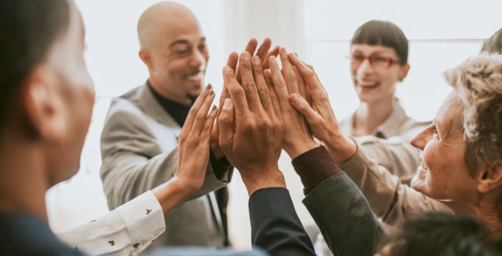 Consulting team high-fiving in celebration, highlighting teamwork made easier with software for consultants.