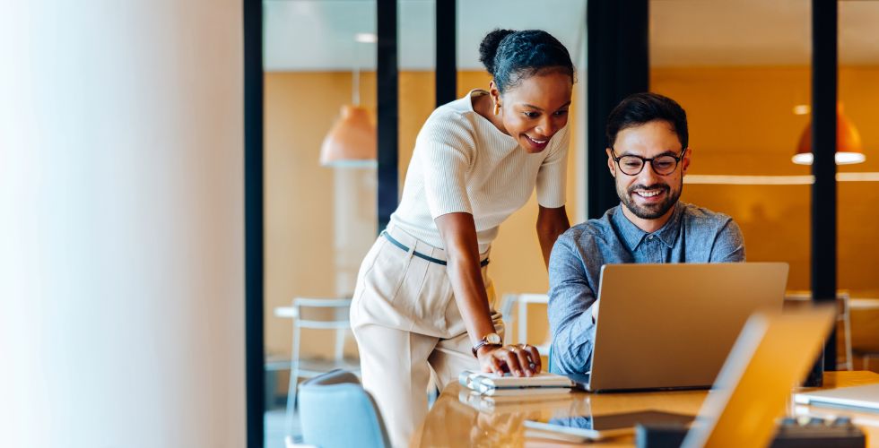 Business development for accountants as two professionals review client data together, identifying advisory opportunities and planning next steps on a laptop in a modern office